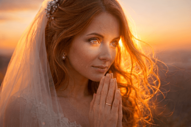 Hooded figure in dark cloak standing on a hill at sunrise